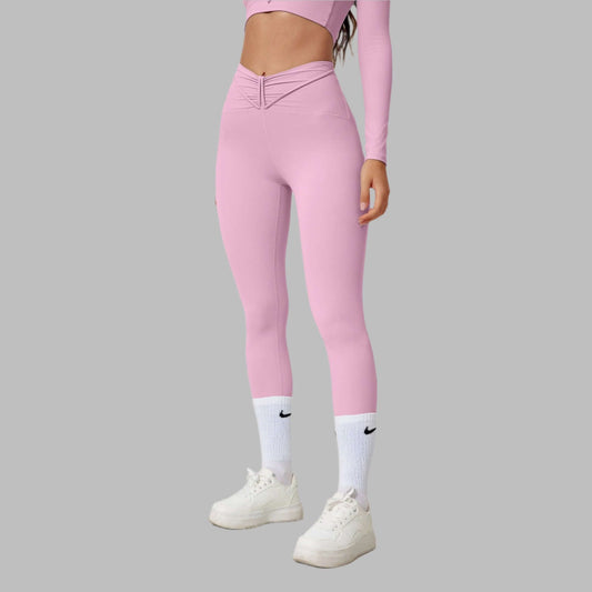 Woman wearing pink seamless shaping leggings and white sneakers on a gray background.