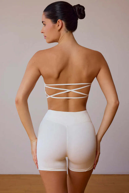 Back view of a woman wearing a white workout beauty set featuring a stylish crisscross strap design, ideal for fitness and lifestyle activities.