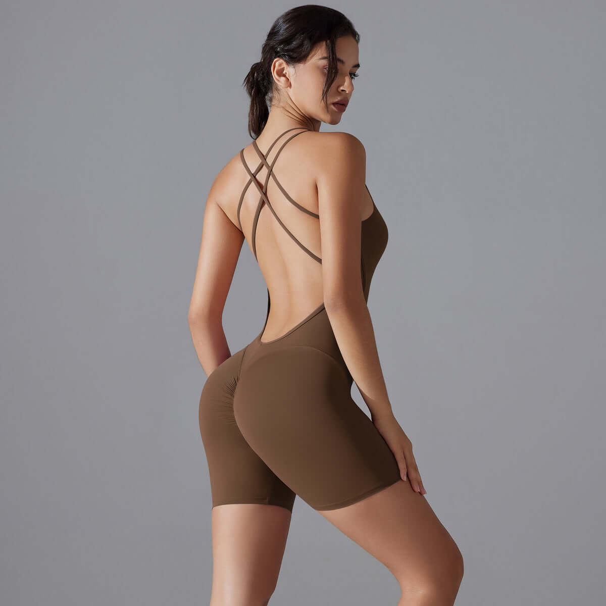 Woman wearing shaping one-piece shorts yoga outfit in brown. Features organic cotton, breathable material, relaxed fit for comfort.