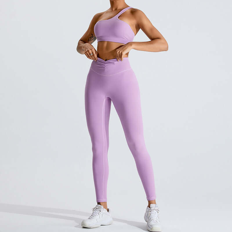 Woman wearing a stylish purple yoga set with leggings and a sports bra, showcasing activewear fashion.