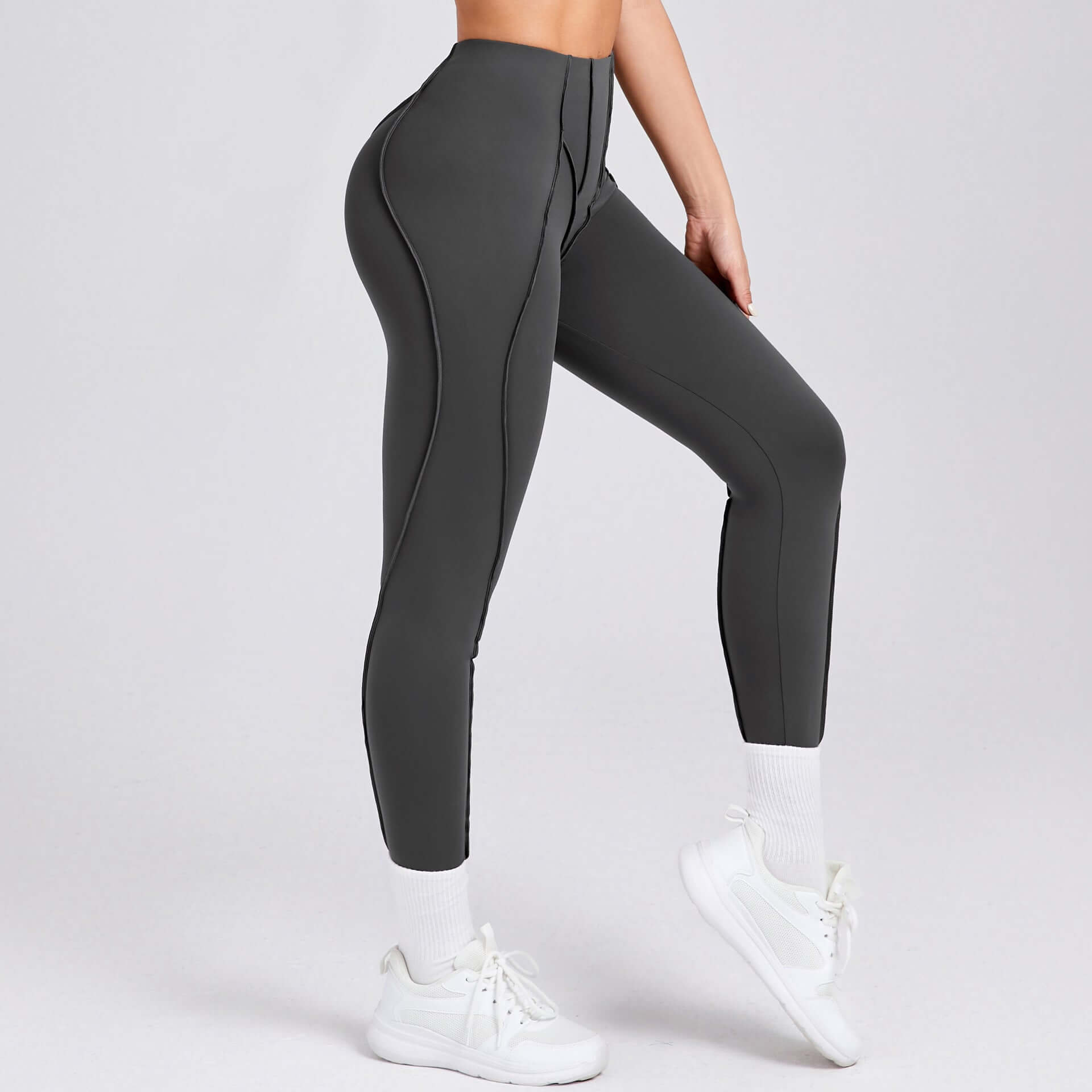 Woman wearing high-waisted compression gym leggings in gray, designed for optimal performance and comfort during workouts.