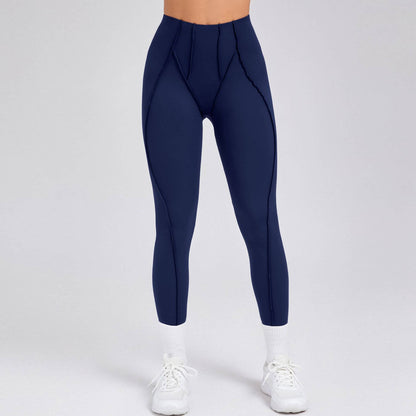 Woman wearing navy blue compression gym leggings with supportive stitching, paired with white sneakers and socks on a neutral background.
