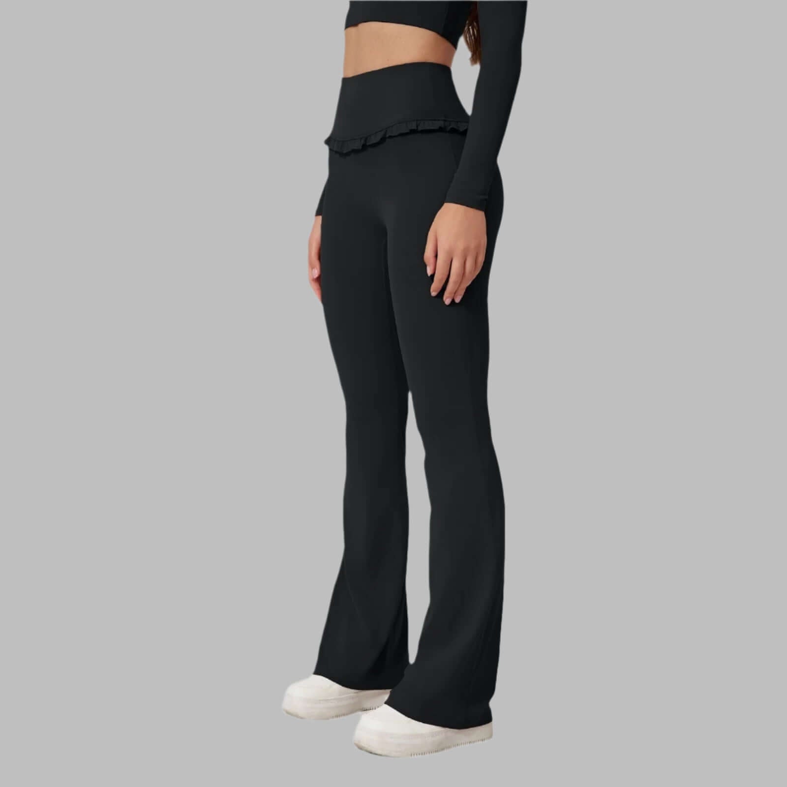 Woman wearing high waist black leggings with flared legs and comfortable fit, side view on a gray background.