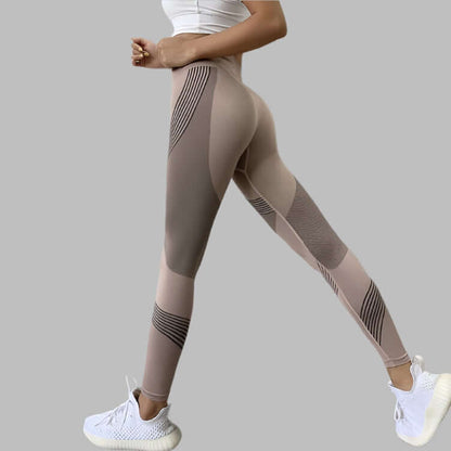 Woman wearing high waist yoga pants with stripe design and white sneakers on a gray background