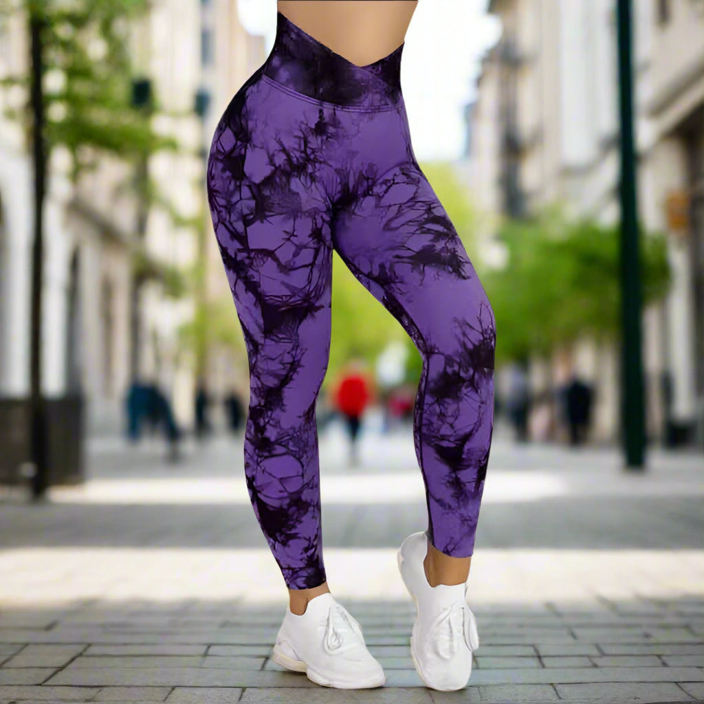 Purple tie dye leggings featuring a high waist fit, paired with white sneakers, showcasing stylish and comfortable activewear.