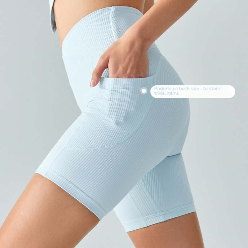 Model wearing blue powder color ribbed sport shorts with spandex fabric, featuring side pockets, suitable for yoga fitness.