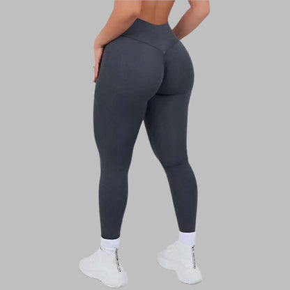 Woman wearing Sculpt Fit Scrunch Leggings in dark grey, showcasing a snug fit and design from behind against a grey background.
