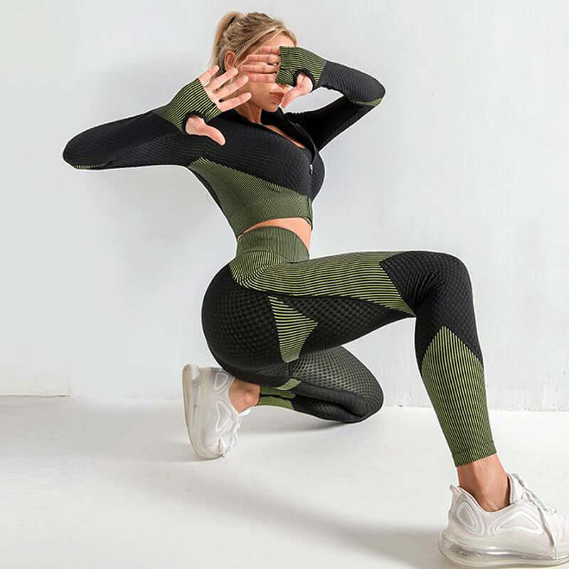 Woman wearing seamless leggings, crop top, and bra in green and black activewear set, performing a workout pose indoors.