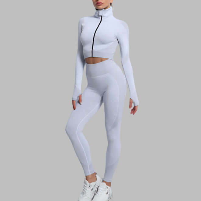 Woman wearing seamless leggings and crop top in white fitness outfit on gray background