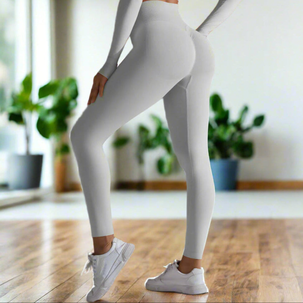 Woman wearing seamless high waist leggings with white sneakers, showcasing a stylish and comfortable fit against a gray background.