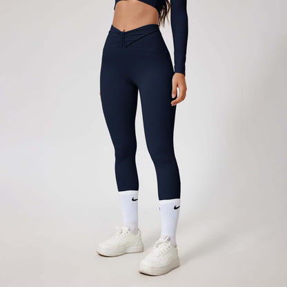 Woman wearing seamless shaping leggings in navy, showcasing sleek design and high-waisted fit, paired with white sneakers.