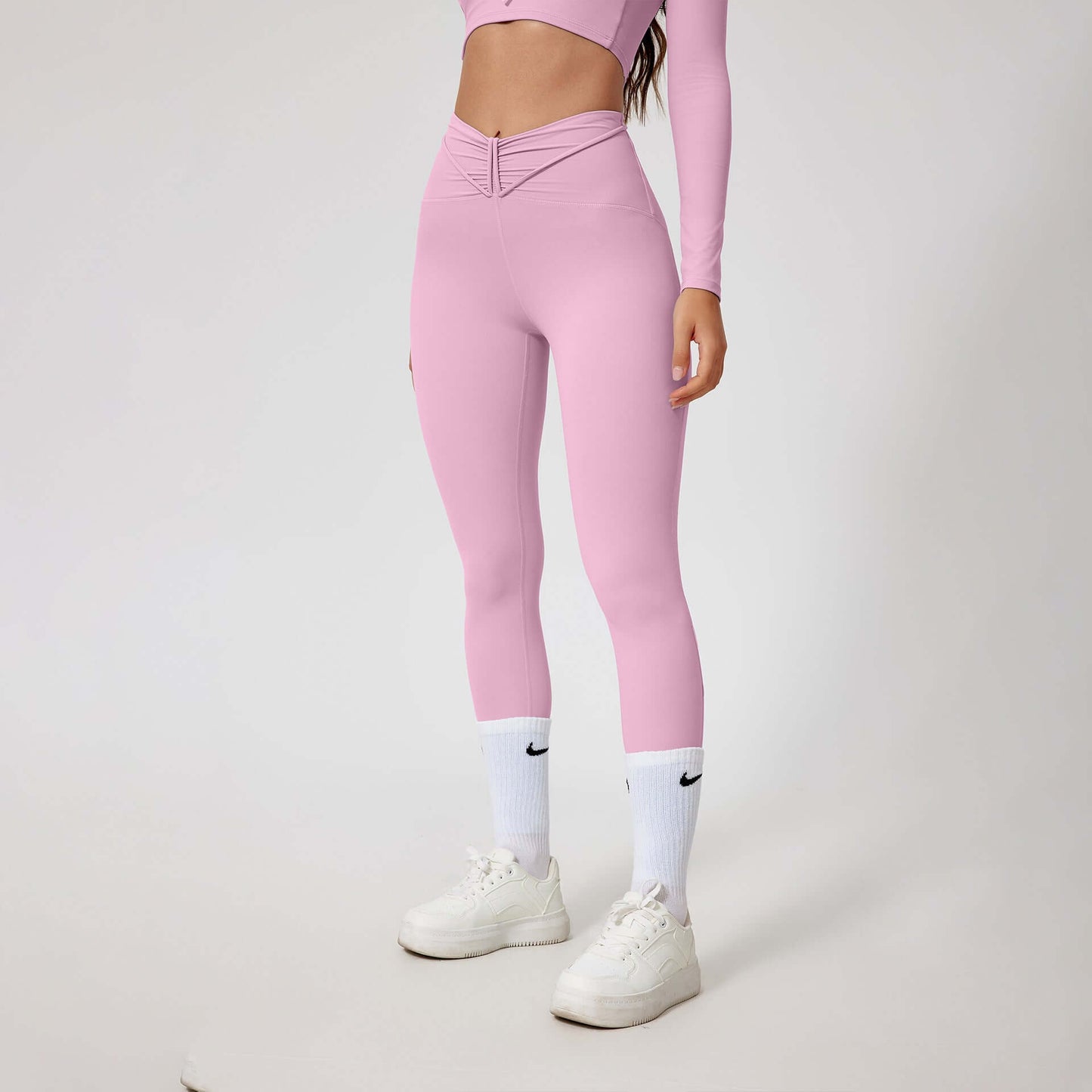 Woman wearing seamless shaping leggings in pink with matching top, white socks, and sneakers, showcasing stylish and comfortable activewear.