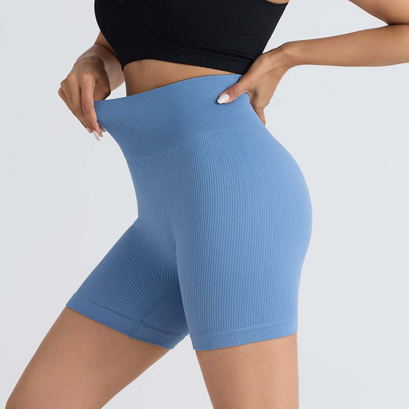 Woman wearing blue seamless stretch shorts, perfect for yoga and fitness, showcasing flexibility and style with a flattering fit.