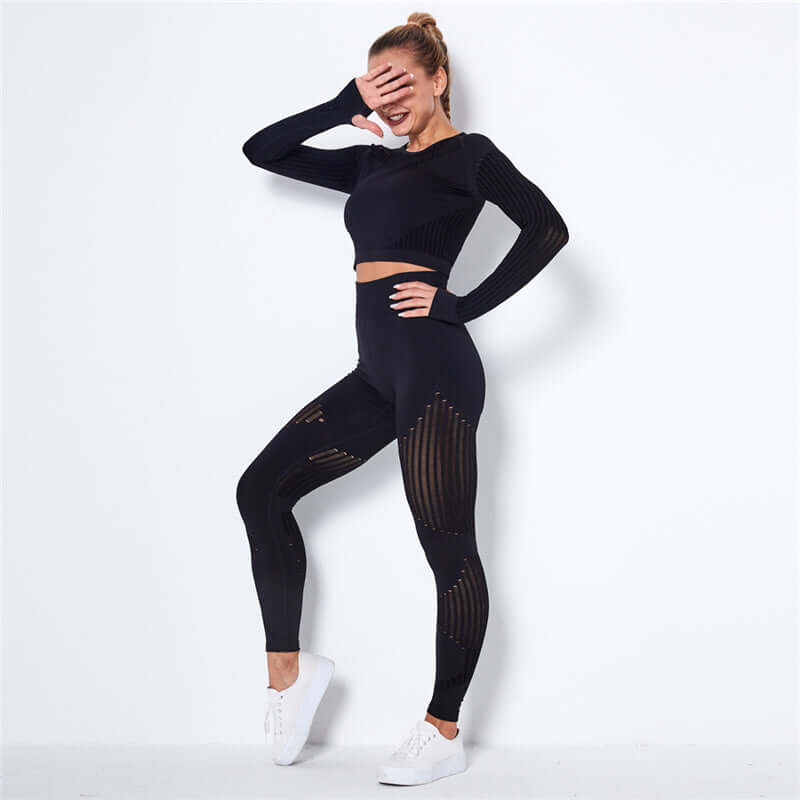 Woman wearing a stylish black striped fitness set including a long sleeve top and leggings, posing confidently.