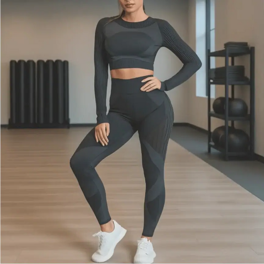 Woman in black striped fitness set posing in gym, wearing leggings and long-sleeve top, showcasing stylish activewear for workouts.