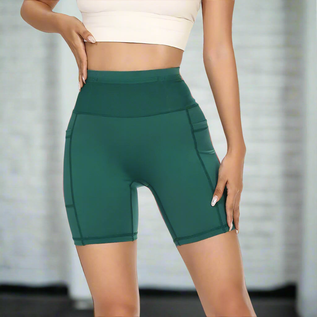 Woman wearing green compression shorts with high waist and pocket detail, perfect for gym or workout sessions.